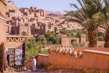 Explore the historic Kasbah Ait Ben Haddou on a 3 Days desert tour from Marrakech to Fes, showcasing ancient architecture, palm trees, and local markets.