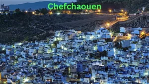 Chefchaouen at night, showcasing its iconic blue-washed buildings, nestled in the Rif Mountains, illuminated by warm street lights on the route to Marrakech.