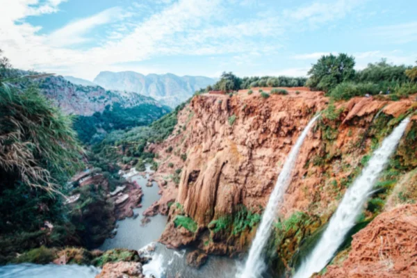 Stunning view of Ouzoud Waterfalls, one of the best places to see in Morocco, surrounded by lush greenery and red cliffs